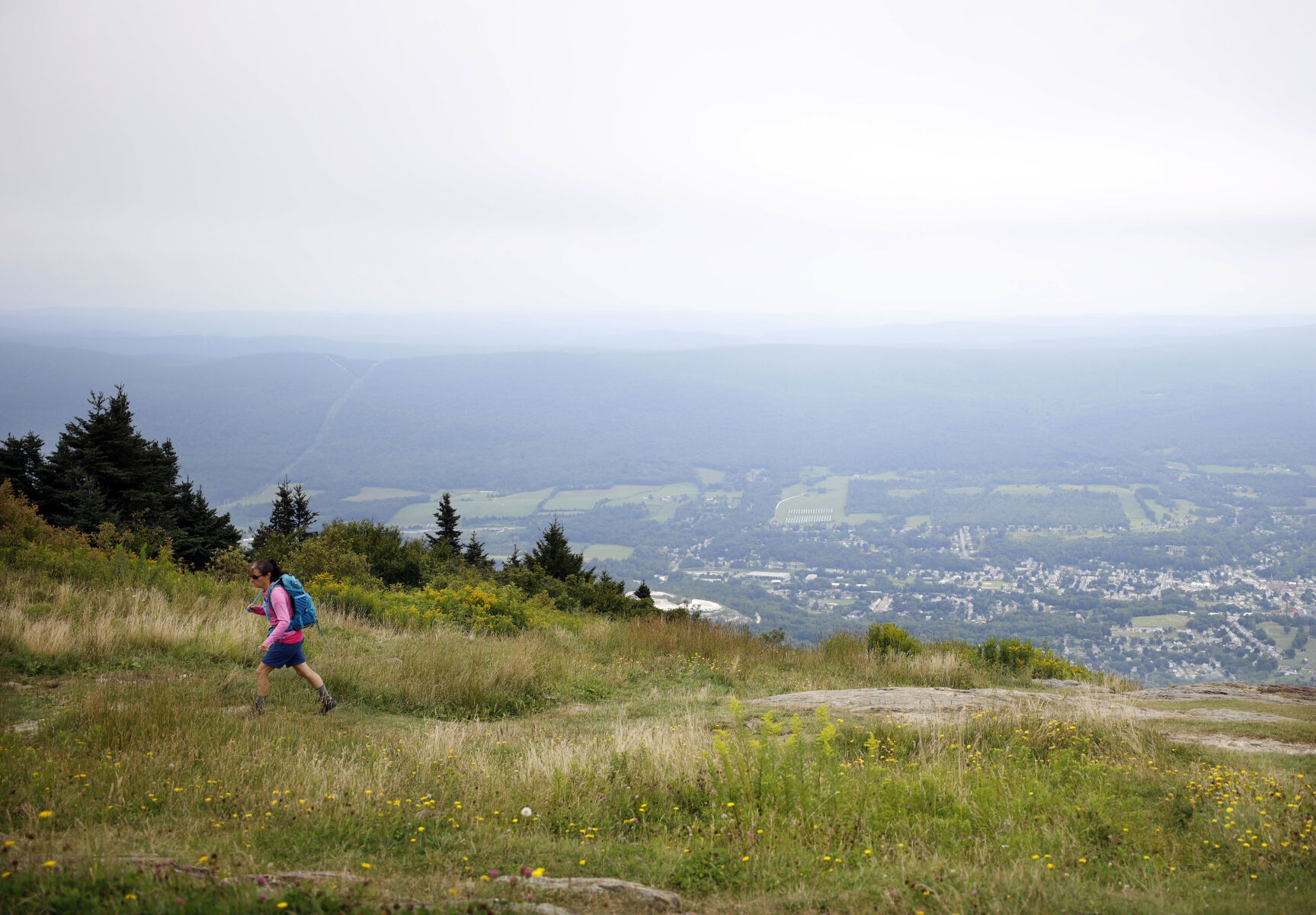 Woman in pink hikes on mountain in front of landscape view of Berkshires